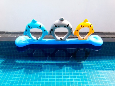 Colorful or cute life ring floating with reflection on the blue swimming pool with white wall...