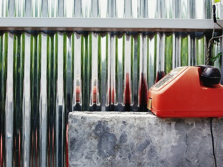 Red vintage, retro or old Telephone with black handset putting on concrete table on zinc wall with copy spaceの写真素材