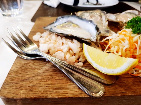Close up fresh mussel with two forks, vegetables, sliced of yellow lemon on the wooden plateの写真素材