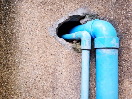 Two blue plastic water pipes inserted into hole of concrete wall - Construction and Industrial conceptの写真素材