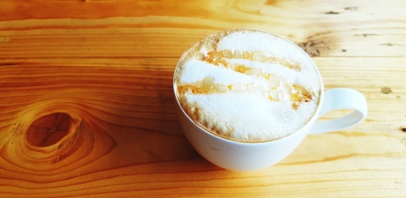 Cup of hot caramel macchiato coffee on the wooden table with copy space at cafÃ© in the morning - Refreshment and Sweet conceptの写真素材