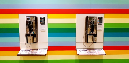 Singapore, Singapore- June 27, 2018: Two public telephone on the rainbow color background at Changi...