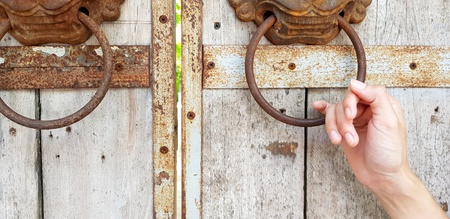 Close up hand holding rusty lion head door knocker on old wooden door background with copy space - Object, Part of body, Vintage style and Decorated conceptの写真素材