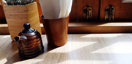Black ceramic tea jug and white napkin putting on wooden table sunlight and copy space - Object,...