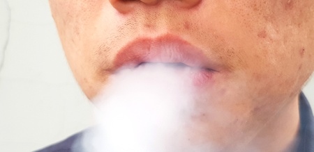 Close up mouth man spraying or smoke cigarette and Selectived focus - Part of human, Mist, Face and Unhealthy life style conceptの写真素材