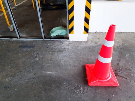 Red traffic cone on concrete floor for restricted area at construction site with copy space -...