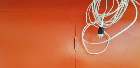White electric wire or cable hanging on wooden orange background with copy space - Electricity,...