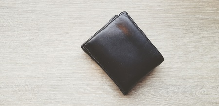 black leather wallet on light brown wooden table or background with copy space - Object, Money and Shape conceptの写真素材