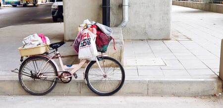 Bangkok, Thailand - March 1, 2019: Old bicycle carry many bag and parked or leaning against footpath on street with big concrete pole background - Street photo and Transportation conceptのeditorial素材