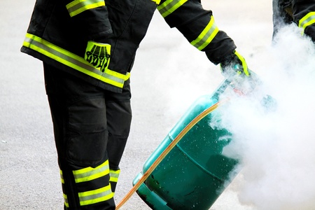 Firefighter using extinguisher and a foam cylinder to fire fighting on green gas tank burning - Rescue, Protective and Dangerous career conceptの写真素材