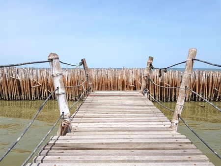Wooden bridge built by people and stretched to seeing tropical sea with clear blue sky and bamboo dam - Beauty of Nature and Pathway for tourist travel to see landscape view and Protection environmentの写真素材