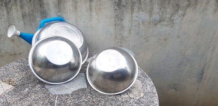 Stainless steel bowl putting and blue plastic watering can on stone table with gray concrete wall background and right copy space - Group of object conceptの写真素材
