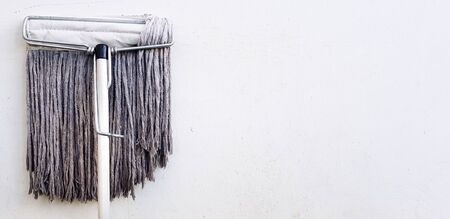 Mop for cleaning floor and house leaning or isolated on white concrete wall with right copy space - Tool, Object, and Cleaner equipment conceptの写真素材