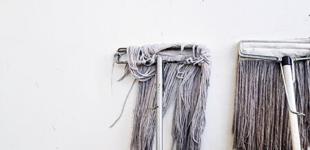 Two mop for cleaning floor and house leaning or isolated on white concrete wall with left copy space...