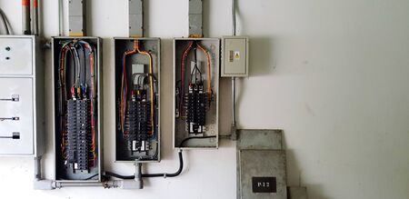 Many circuit breaker for distribute electricity in building on white wall with right copy space in...
