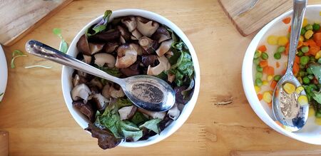 Flat lay of bowl of mushroom with sliced green bean, carrot and corn with stainless steel spoon on...