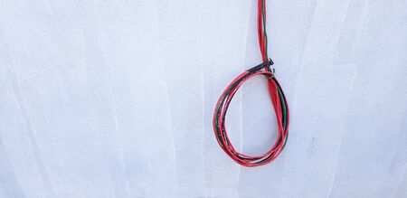 Red, Black, and Green cable hanging or isolated on gray concrete wall with copy space - New installation wiring power cord, Connection, Repair building and Electrical system industrial conceptの写真素材