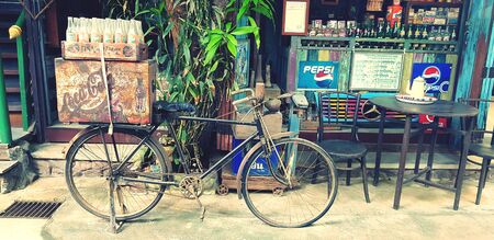 Ratchaburi, Thailand - September 26, 2018: Vintage bicycle parked and container old box and glass bottle in front of retro cafe - Classic stuff and Old style conceptのeditorial素材