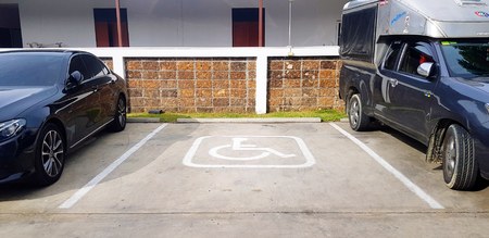 Songkhla, Thailand - May 19, 2019: The reservation parking of disabled people in middle or center between black car with brown brick wall background - Symbol, Restrict area and Reserve service conceptのeditorial素材