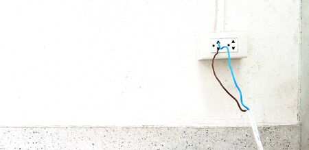 Bare blue and brown wire in white cable install and plug in to electrical outlet box on white cement...