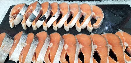 Many fresh sliced of salmon on black tray putting on ice for customer buy and sale at fish marketの写真素材