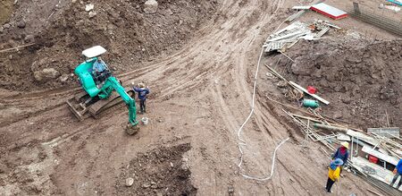 Phetchabun, Thailand - July 6, 2019: Top view or Aerial of construction site with labor, buildings and green backhoe or Crawler Loader digging landのeditorial素材