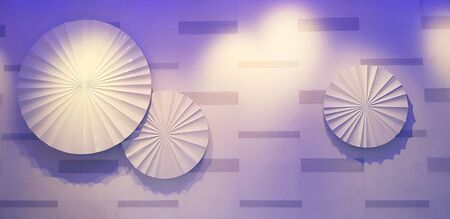 Three White umbrellas with one big and two small hanging and decorated on white wall with purple or...
