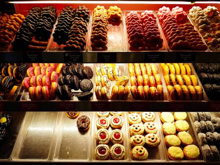 Many donuts with chocolate frosted, strawberry frosted, sprinkles donuts cream and pink glazed on...