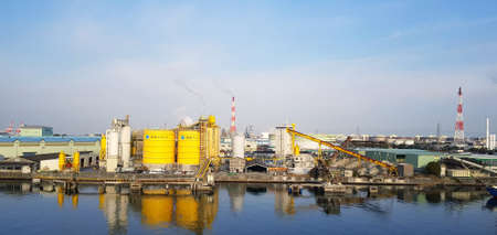 Japan - February 20, 2019: Many factory of industrial type are located near the river with clear blue sky background and above copy space. Factory emits pollutants into atmosphere. Pollution conceptのeditorial素材