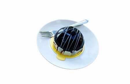 Smooth chocolate cake with milk sauce and blueberry on top with fork in white plate isolated on white background. Sweet dessert and food conceptの写真素材