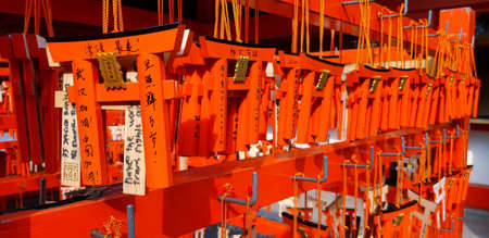 Kyoto, Japan  - February 22, 2019: Many small Torii Gate hanging on red wooden hanger at Fushimi Inanari Shrine. People write blessings on amulets and prayed to be true.のeditorial素材