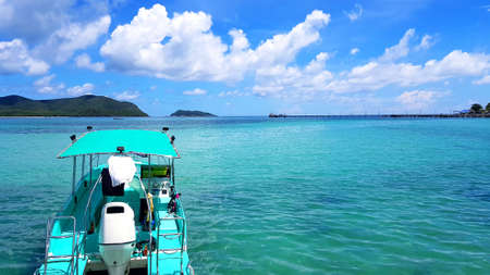 Green speed boat parked or floating on clear Andaman sea or ocean with mountain, white clouds and blue sky and copy space on right. Beauty in nature. Tour or Trip on summertime in East of Thailandの写真素材