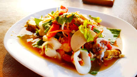 Close up Thai spicy salad mixed with fresh squid, Thai sausage, shell, shrimp, slices of tomato, carrot, onion, chili, garlic,
Bok choy and lemon water. Famous Asian food for diet and health.の写真素材