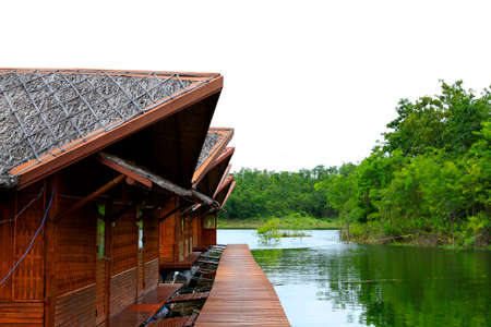 Wooden houses floating on river or lake for tourist take rest and chill out among beauty of nature with green tree background at Amadard resort, Kanchanaburi, Thailand. Landmark of Asia travel.のeditorial素材