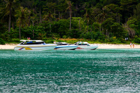 Speed boat parked or floating on the sea with coconut or palm and forest on island for background. Beauty in nature at south of Thailand. Tourist walking on the beach. Landmark for travel.の写真素材