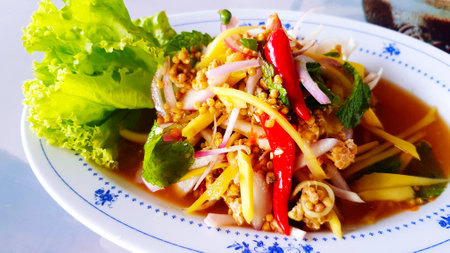 Thai spicy horseshoe crab egg Salad or pimp eggs with slice of sour mango and green lettuce on white plate or dish at seafood restaurant. Asian and diet foodの写真素材