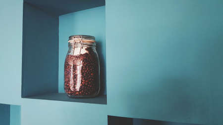 Glass bottle of coffee seed putting on green wooden self and wall background for sale or decorated at cafÃ© shop in vintage tone with copy space on right.の写真素材