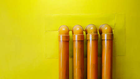 Four yellow water pipeline on yellow concrete wall for background with copy space. Oil pipe installed on floor.の写真素材