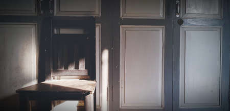 Wooden chair with shade of sunlight on vintage or classic door. Retro object with light in morning.