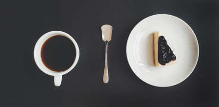 Top view of blueberry cheese cake, black of coffee and tea spoon on black background in vintage...