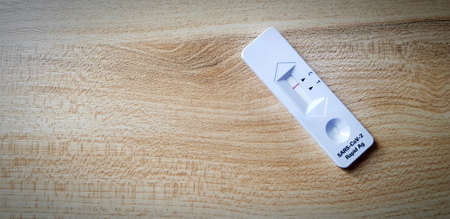Covid antigen test kit on wooden table with copy space for people testing infected with virus by by...