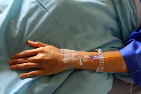 Close up the patient's hands and arms are giving the saline solution on bed with copy space....