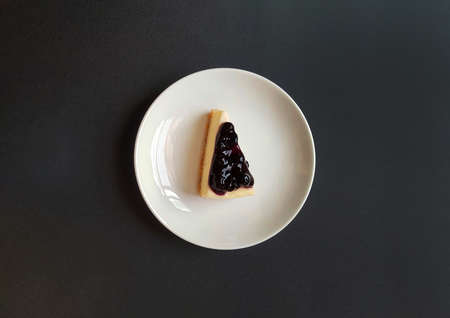 Top view of slice of blueberry cheesecake in white dish or plate with copy space. Flat lay of sweet...