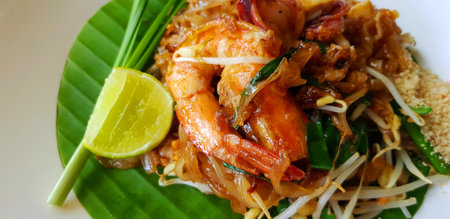Close up stir fried with rice noodle, river prawn or shrimp, bean sprout, sliced chives and lime on banana leaf with copy space. Famous food in Thailand call Pad Thai. Selective foの写真素材