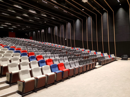 Modern auditorium, cinema hall or movie theater with rows of red, blue, black, gray or grey and white seats or chairs. Beautiful room interior design with furniture.の写真素材