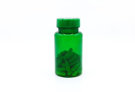 Green plastic bottle of pills or capsules isolated on white background. Healthy food, herbs, container object and Medicin e. Food supplements for cure or repair health.の写真素材