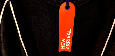 Orange paper with copy space or blank price tag for add text or number of price putting on black t-shirt or coat background. New arrival for cloth.の写真素材