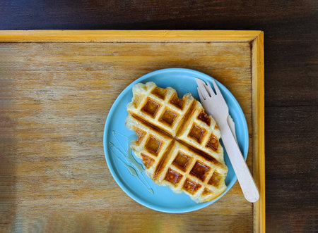 Top view of waffle topped with honey sauce on blue plate at cafe. Flat lay of Sweet bakery on dish with copy space.の写真素材