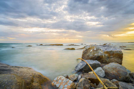 big rock on the beach at sunset momentの写真素材