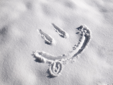 Smile emoji painted on the snow, close-upの写真素材